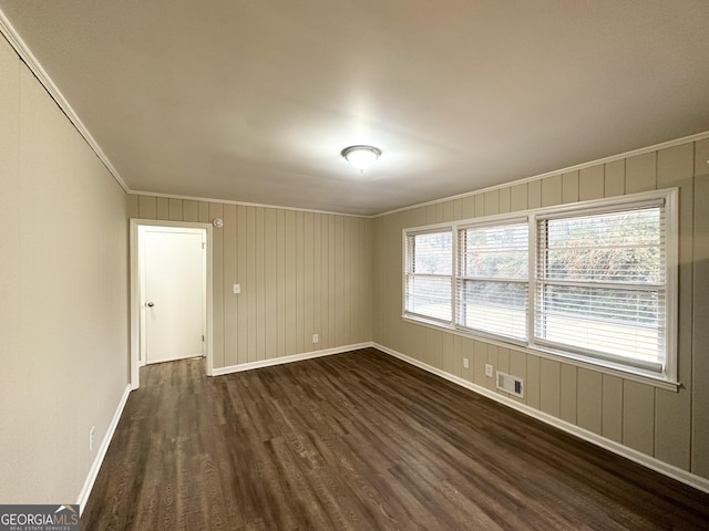 spare room with dark wood-type flooring, ornamental molding, and a healthy amount of sunlight