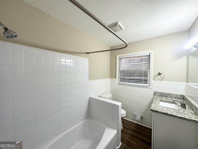 full bathroom with toilet, tile walls, shower / tub combination, vanity, and hardwood / wood-style flooring