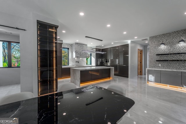 kitchen with backsplash, decorative light fixtures, and a center island