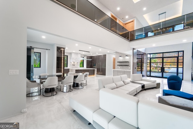 living room featuring a wealth of natural light, a barn door, and a high ceiling