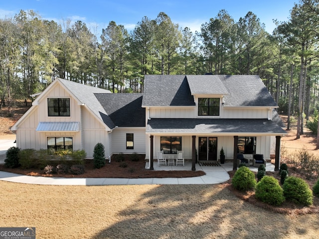 view of front of home with board and batten siding, roof with shingles, and a patio