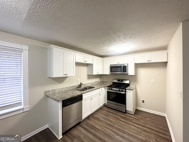 4954 Springbrook Dr, Douglasville, GA 30135 - kitchen with stainless steel appliances, white cabinetry, dark wood finished floors, a textured ceiling, and light stone countertops