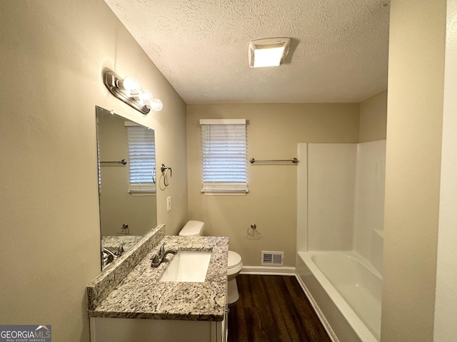bathroom featuring vanity, toilet, hardwood / wood-style floors, and a textured ceiling