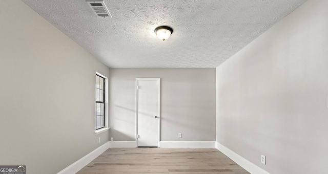 empty room featuring light hardwood / wood-style floors and a textured ceiling