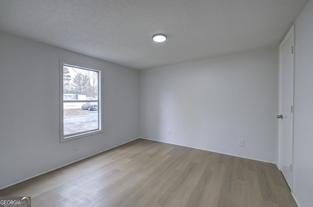 unfurnished room with light hardwood / wood-style floors and a textured ceiling