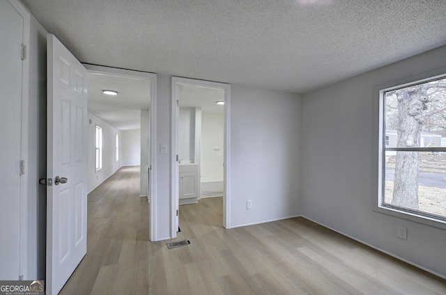 empty room with light hardwood / wood-style flooring and a textured ceiling