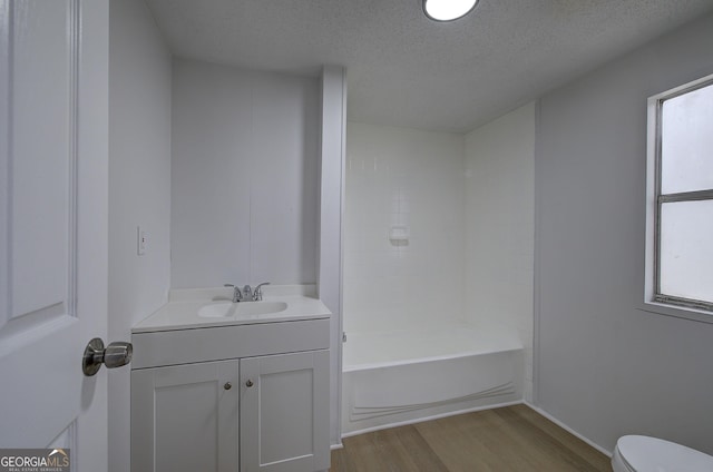 full bathroom featuring toilet, a textured ceiling, vanity, shower / bath combination, and hardwood / wood-style floors