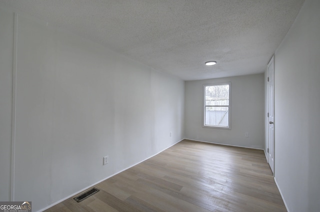 spare room featuring a textured ceiling and light wood-type flooring