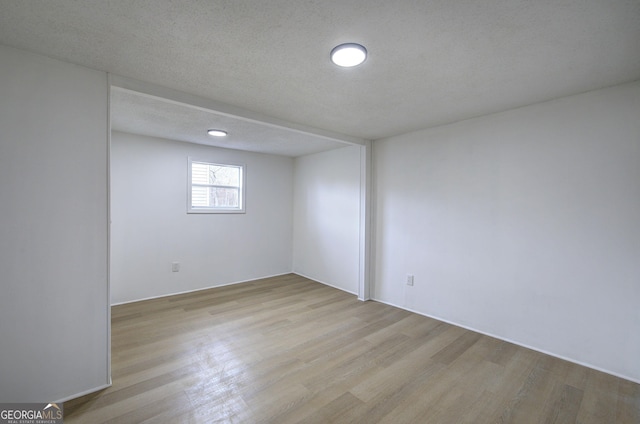 unfurnished room with a textured ceiling and light wood-type flooring