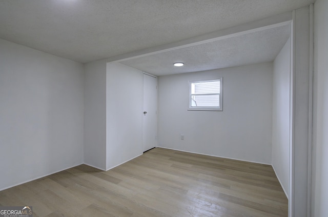 empty room featuring a textured ceiling and light hardwood / wood-style flooring