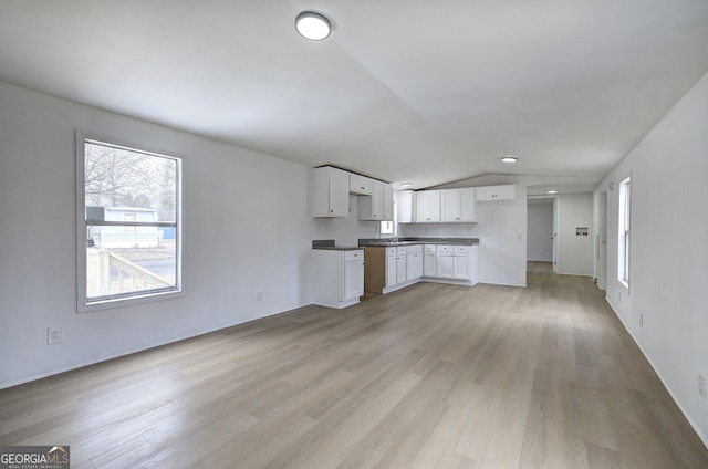 kitchen featuring lofted ceiling, white cabinets, and light wood-type flooring