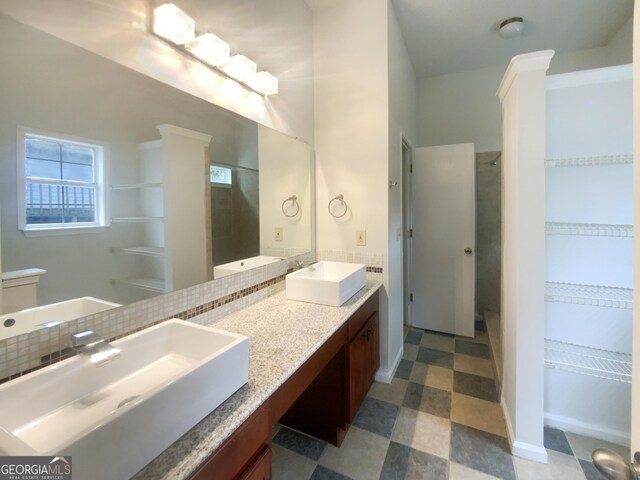 bathroom with tasteful backsplash, vanity, a shower, and ornate columns