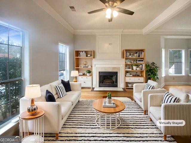 living room with beamed ceiling, ornamental molding, ceiling fan, and light hardwood / wood-style floors