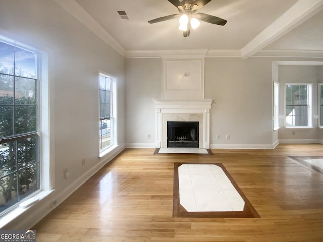 unfurnished living room featuring ceiling fan, ornamental molding, a high end fireplace, and light hardwood / wood-style floors