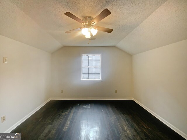 additional living space with ceiling fan, dark hardwood / wood-style flooring, vaulted ceiling, and a textured ceiling