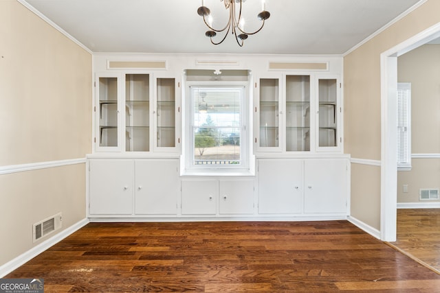 unfurnished dining area featuring ornamental molding, dark hardwood / wood-style floors, and a chandelier