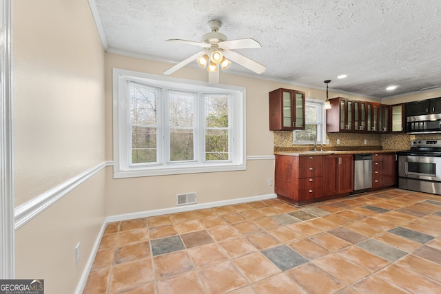 kitchen with pendant lighting, crown molding, dark stone countertops, stainless steel appliances, and tasteful backsplash