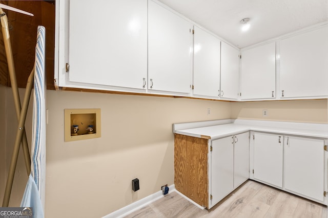 laundry room with hookup for a washing machine, cabinets, and light wood-type flooring