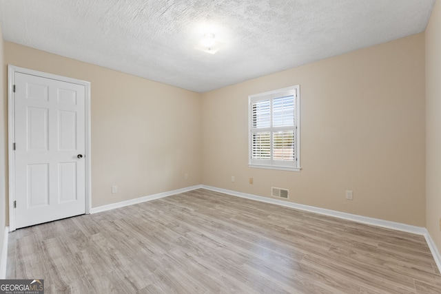 empty room with a textured ceiling and light wood-type flooring