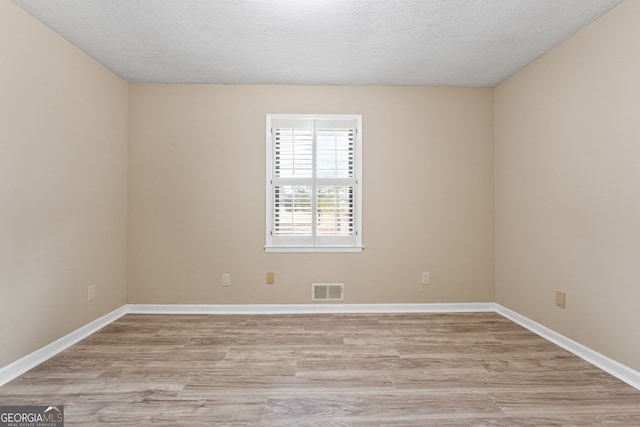 unfurnished room with a textured ceiling and light wood-type flooring