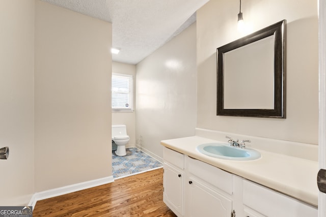 bathroom featuring vanity, toilet, hardwood / wood-style floors, and a textured ceiling