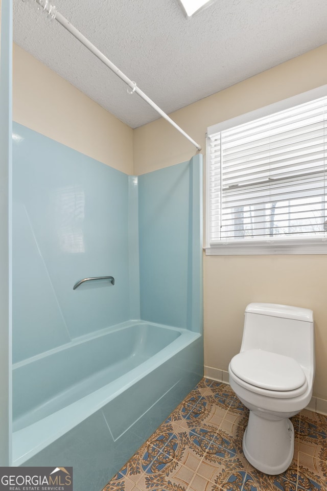 bathroom featuring bathtub / shower combination, tile patterned floors, toilet, and a textured ceiling