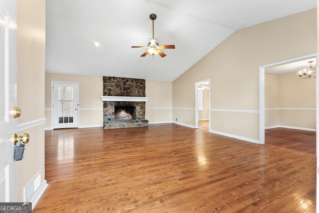 unfurnished living room featuring hardwood / wood-style flooring, vaulted ceiling, and a stone fireplace