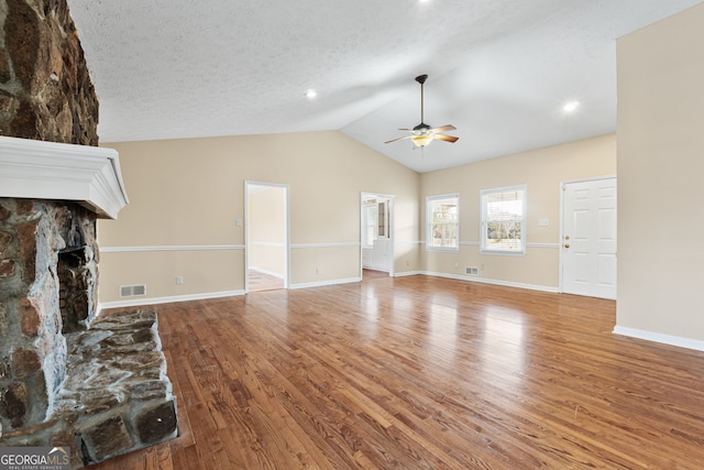 unfurnished living room featuring ceiling fan, wood-type flooring, a fireplace, and lofted ceiling