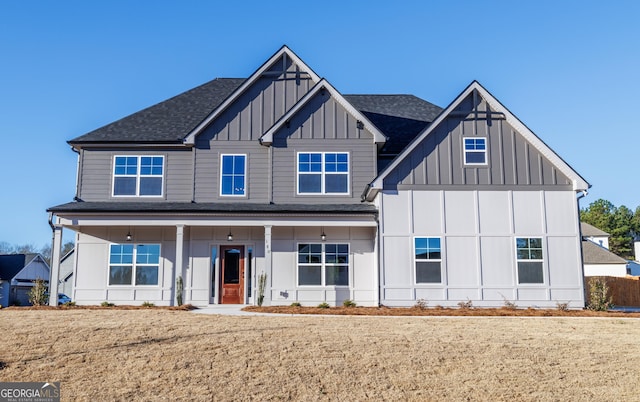 view of front of house featuring board and batten siding, a shingled roof, and a front lawn