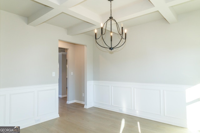 unfurnished dining area with light wood-style flooring, coffered ceiling, beamed ceiling, and wainscoting