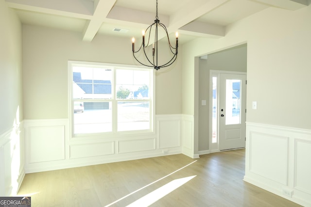 doorway with light wood-type flooring, a wealth of natural light, wainscoting, and beamed ceiling