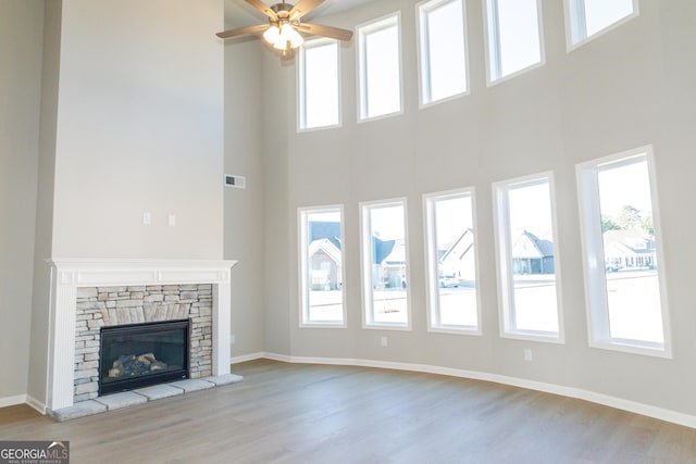 unfurnished living room featuring baseboards, a fireplace, visible vents, and wood finished floors