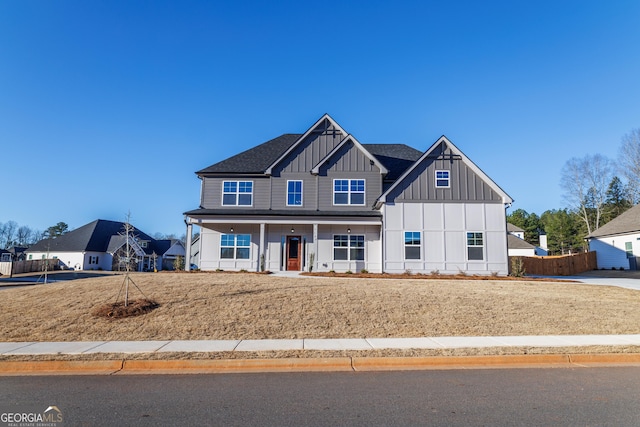 view of front of property featuring board and batten siding, fence, and a porch