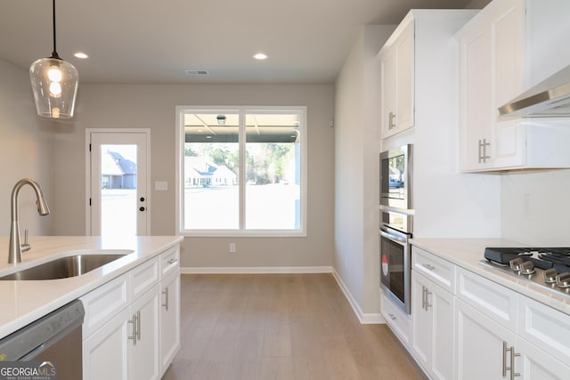 kitchen with a healthy amount of sunlight, wall chimney range hood, stainless steel appliances, and a sink