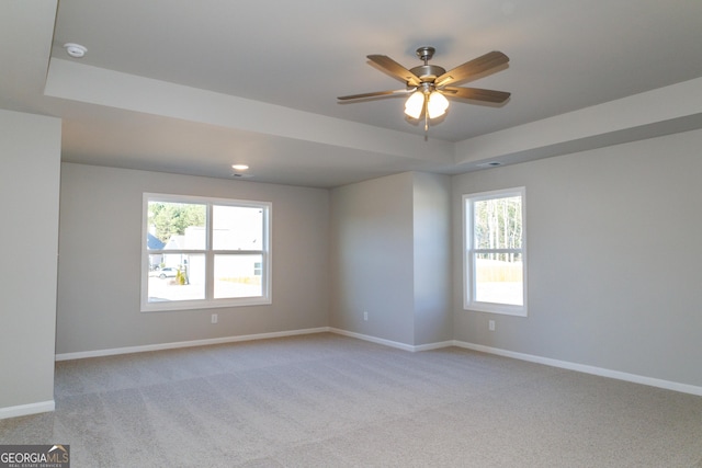 spare room featuring baseboards, a tray ceiling, ceiling fan, and light colored carpet