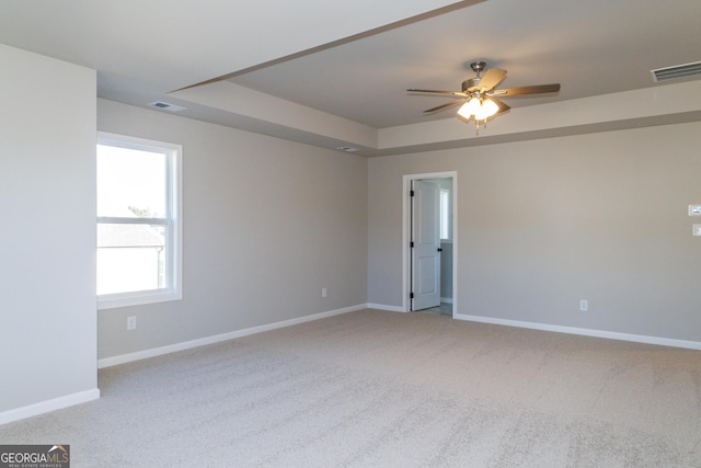 empty room featuring baseboards, carpet, visible vents, and a tray ceiling