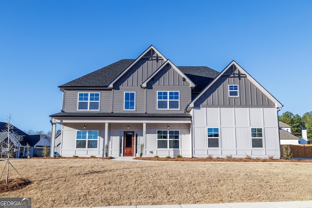 view of front of property with board and batten siding, a front yard, and a shingled roof