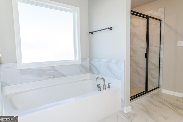 bathroom with marble finish floor, a shower stall, a bath, and baseboards