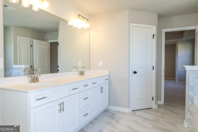 full bath featuring marble finish floor, a sink, baseboards, and double vanity