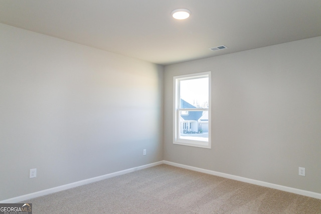 empty room with visible vents, light carpet, and baseboards