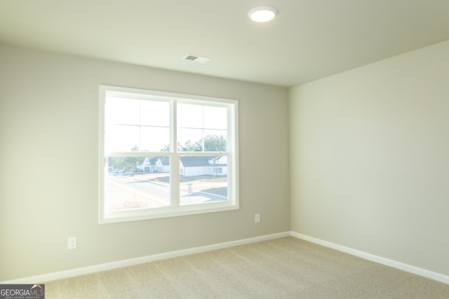 carpeted spare room featuring visible vents and baseboards