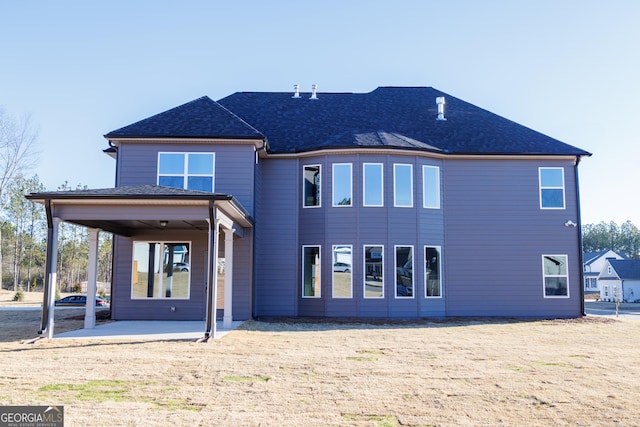 rear view of property with a patio and a shingled roof