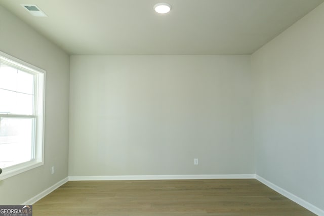 empty room featuring light wood finished floors, visible vents, and baseboards