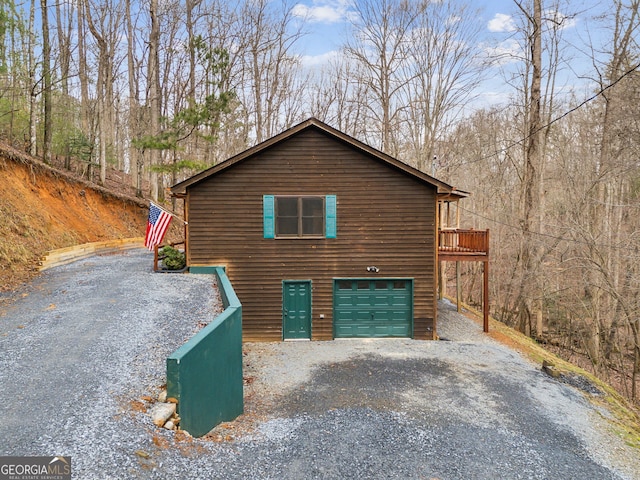 view of property exterior featuring a garage, driveway, and a wooded view