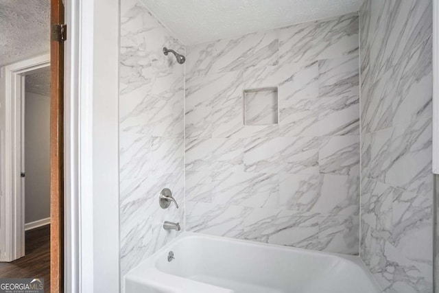 bathroom featuring tiled shower / bath, wood-type flooring, and a textured ceiling