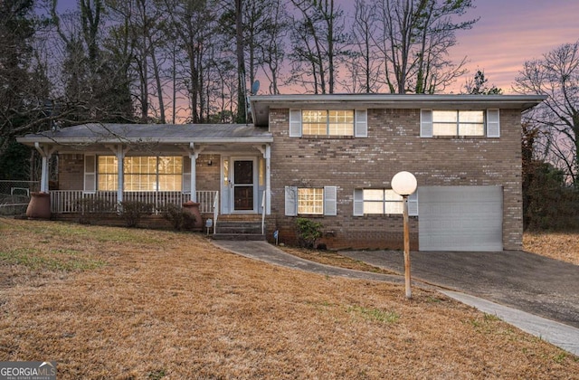 tri-level home featuring a porch, a garage, and a yard