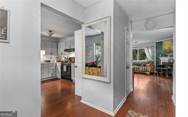 kitchen with black range oven, dark hardwood / wood-style flooring, and a textured ceiling