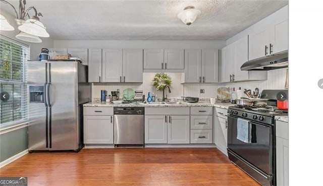 kitchen featuring wood-type flooring, appliances with stainless steel finishes, sink, and backsplash