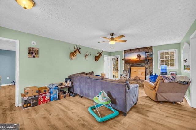 living room featuring ceiling fan, a textured ceiling, and light wood-type flooring