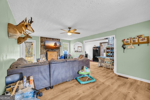 living room featuring ceiling fan, a healthy amount of sunlight, a textured ceiling, and light hardwood / wood-style floors